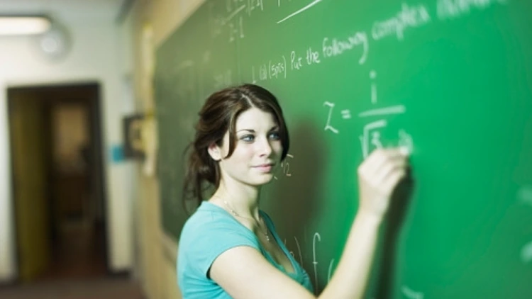 אישה פותרת תרגיל מתמטי על לוח