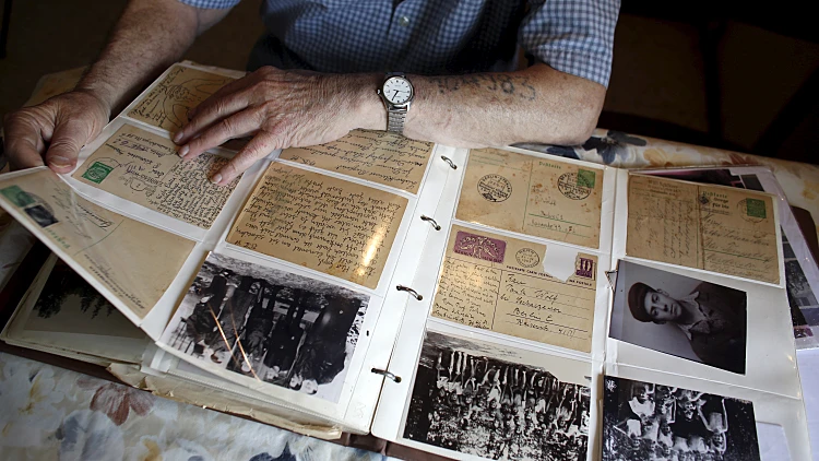 ניצול השואה ישראל לוינשטיין מסתכל באלבום תמונות