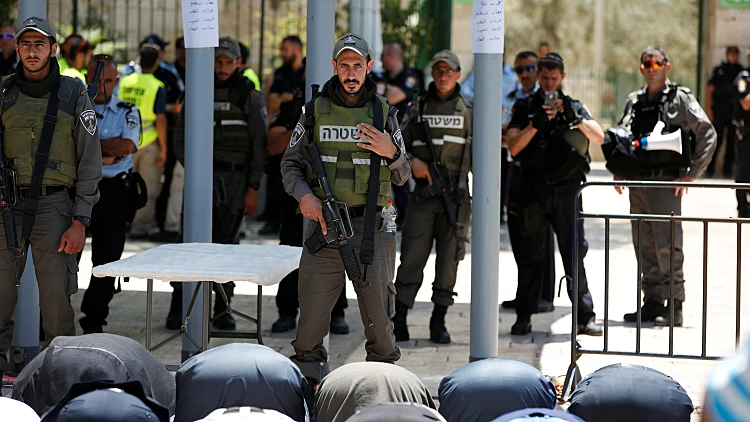 מוסלמים מתפללים מול שוטר מג"ב ישראלי בכניסה להר הבית