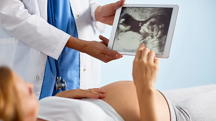 אישה בהריון מביטה בתוצאות בדיקת אולטרסאונד