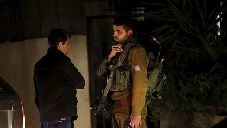 חייל צה"ל מתשאל פלסטיני באזור חברון, שם נערכים חיפושים אחר הנעדר הישראלי