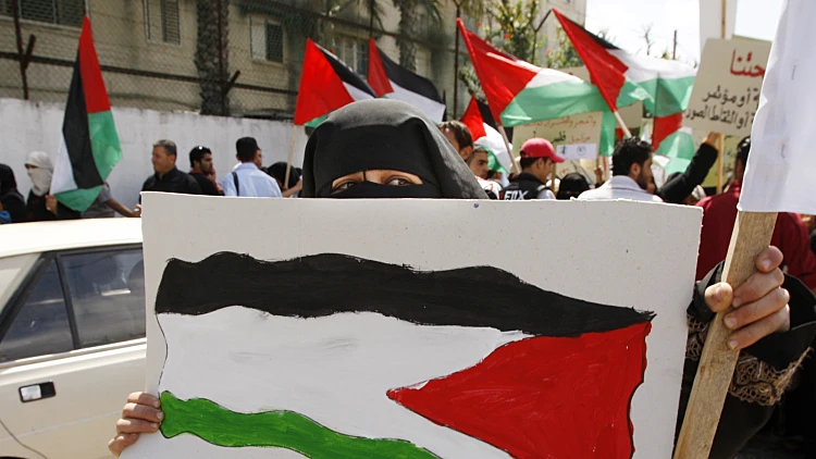 פלסטינית מחזיקה שלט בעד אחדות פלסטינית