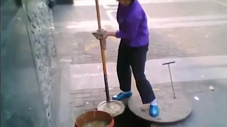אישה בסין מוציאה מי ביוב לצורך הכנת שמן