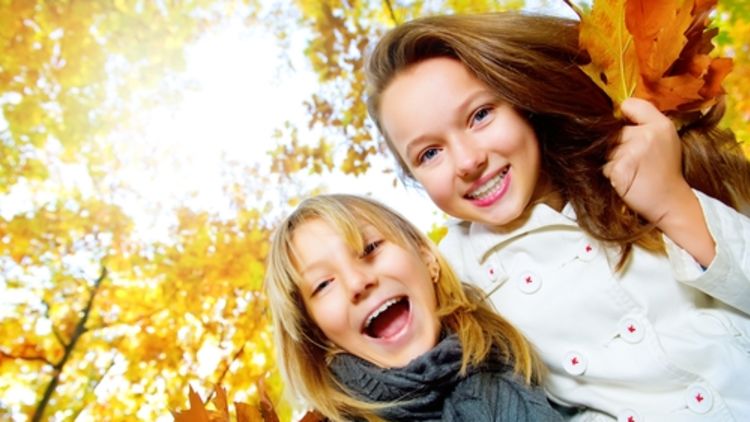 שתי נערות מחייכות על רקע יער בשלכת