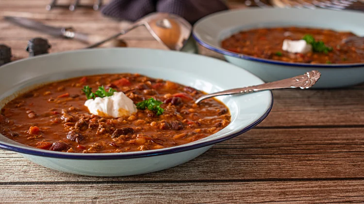 Rustic,beans,stew,with,meat,and,sour,cream,topping,served