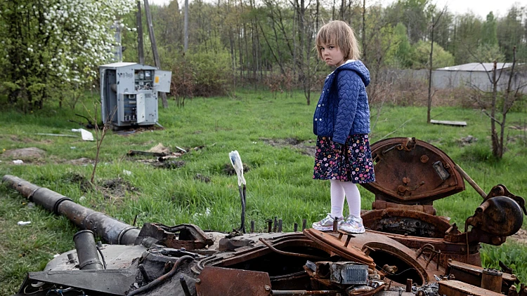 ילדה עומדת על טנק רוסי שרוף סמוך לקייב בירת אוקראינה