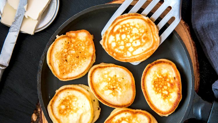 Small,pancakes,in,a,pan,on,a,wooden,board.