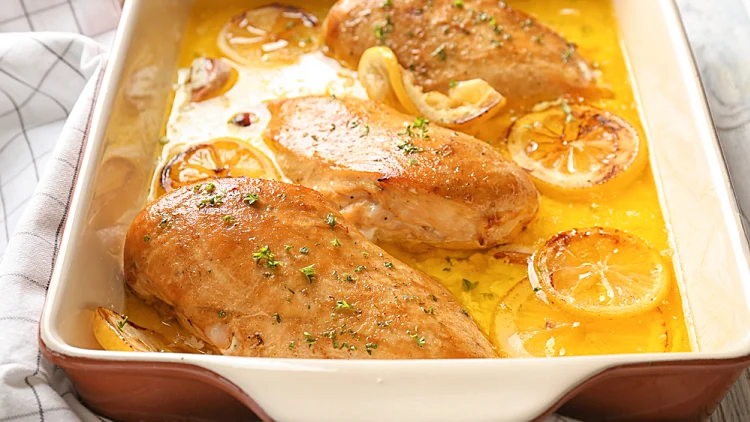 Delicious,chicken,breasts,with,lemon,in,baking,dish,on,table