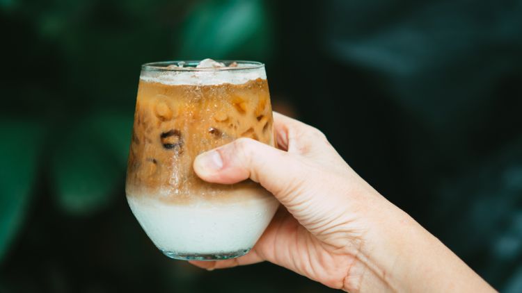 Hand,hold,ice,latte,coffee,in,a,glass,with,cream