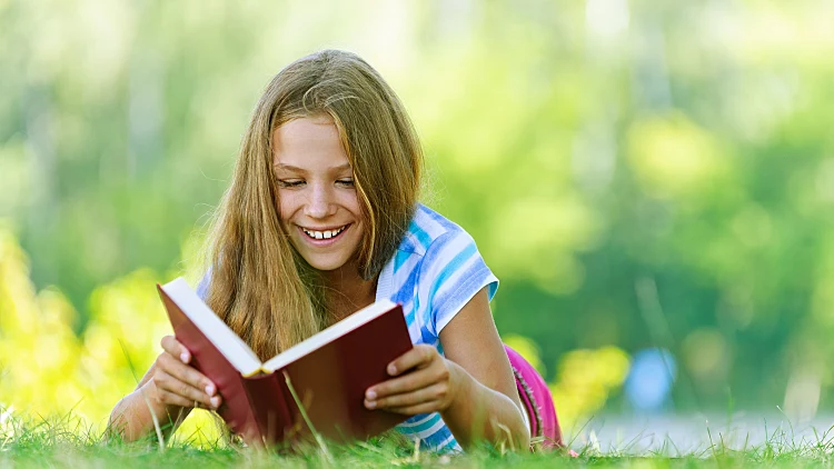 נערה קוראת ספר על הדשא