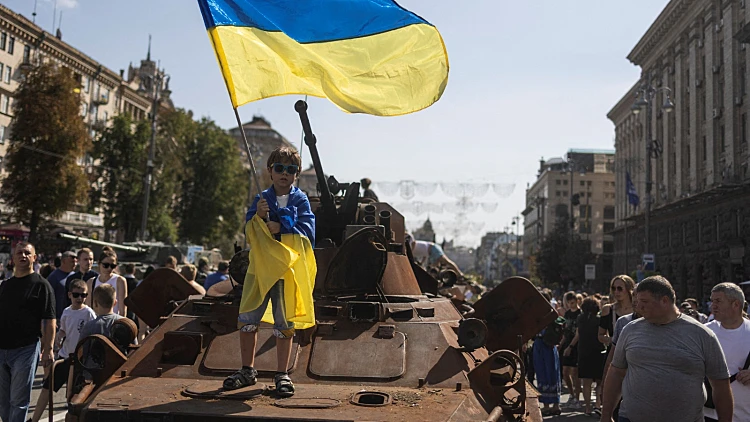 ילד מניף דגל אוקראינה על טנק רוסי הרוס בקייב