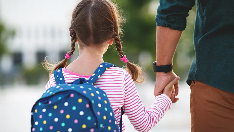 ילדה אוחזת את היד של אביה בדרך לבית הספר