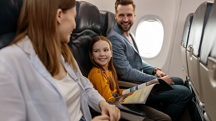 Cheerful,little,girl,traveling,with,parents,on,airplane