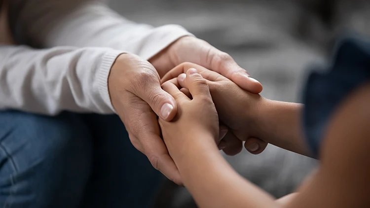 Close,up,compassionate,young,foster,parent,holding,hands,of,little