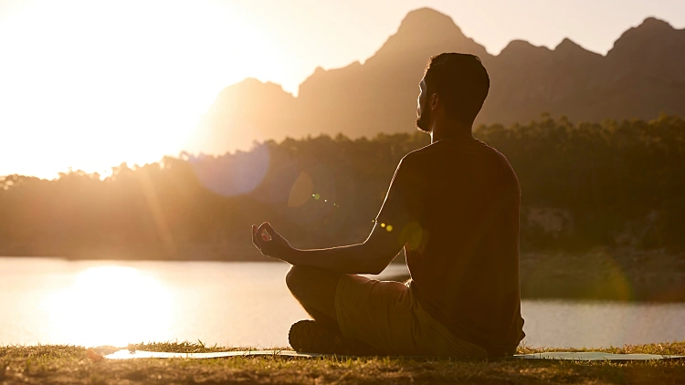 Man,meditating,doing,yoga,by,lake,and,mountains,at,sunset