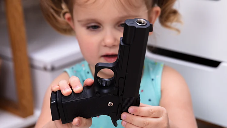 Close Up,of,little,girl's,hand,holding,gun,at,home
