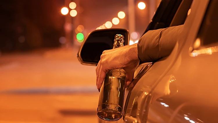 Drunk,man,driving,a,car,with,a,bottle,of,beer