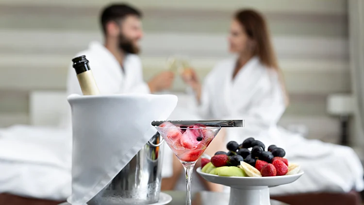 זוג רומנטי בחדר במלון עם פירות ושמפנייה