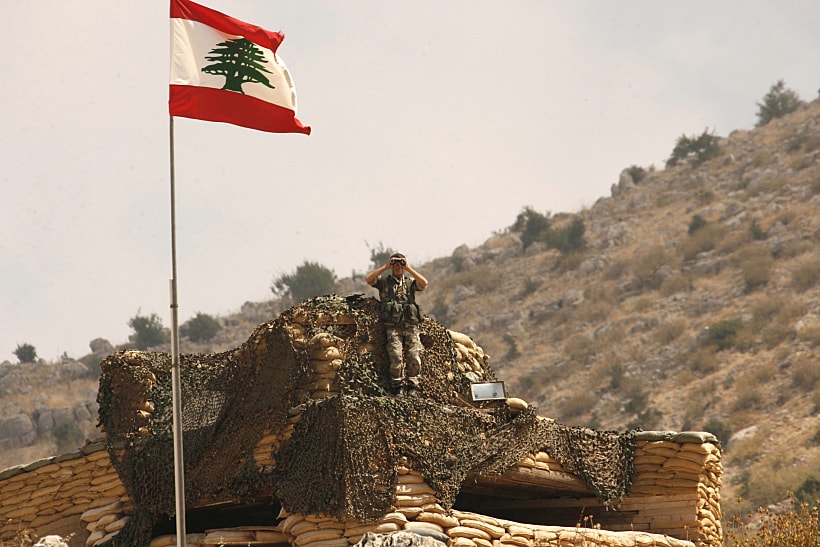 חייל לבנוני מסתכל במשקפת על חוות שבעא בגבול לבנון