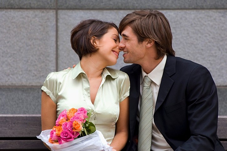 גבר ואישה מתנשקים. האישה מחזיקה פרחים