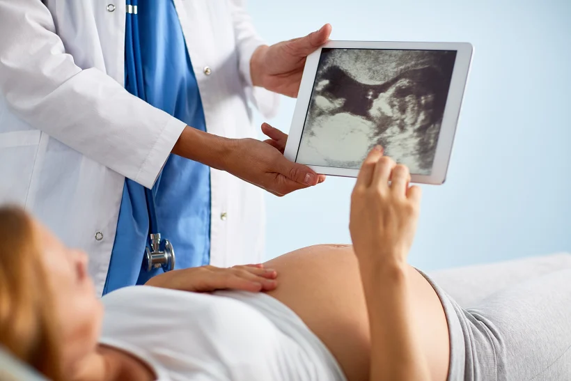 אישה בהריון מביטה בתוצאות בדיקת אולטרסאונד