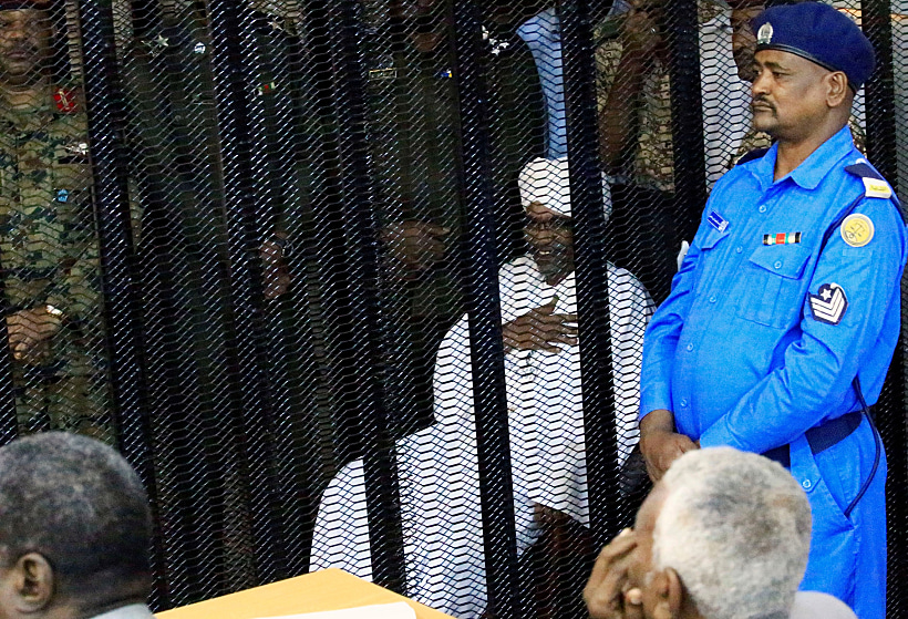 Sudan's Former President Omar Hassan Al Bashir Sits Guarded Inside A Cage At The Courthouse Where He Is Facing Corruption Charges, In Khartoum