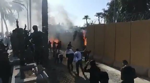מפגינים מבעירים את החומה סמוך לשגרירות ארה''ב בבגדאד