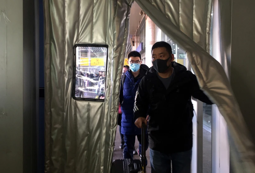 נוסעים עוטים מסכות רפואיות בתחנת רכבת בבייג'ינג