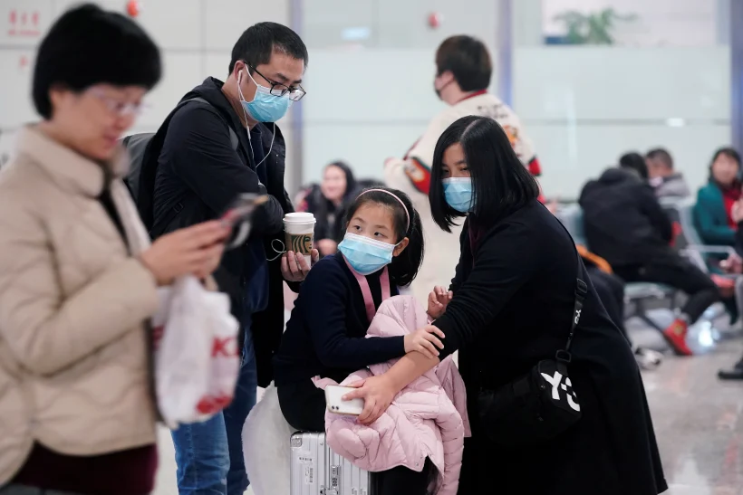 נוסעים עוטים מסכות בשדה התעופה בשאנגחאי שבסין