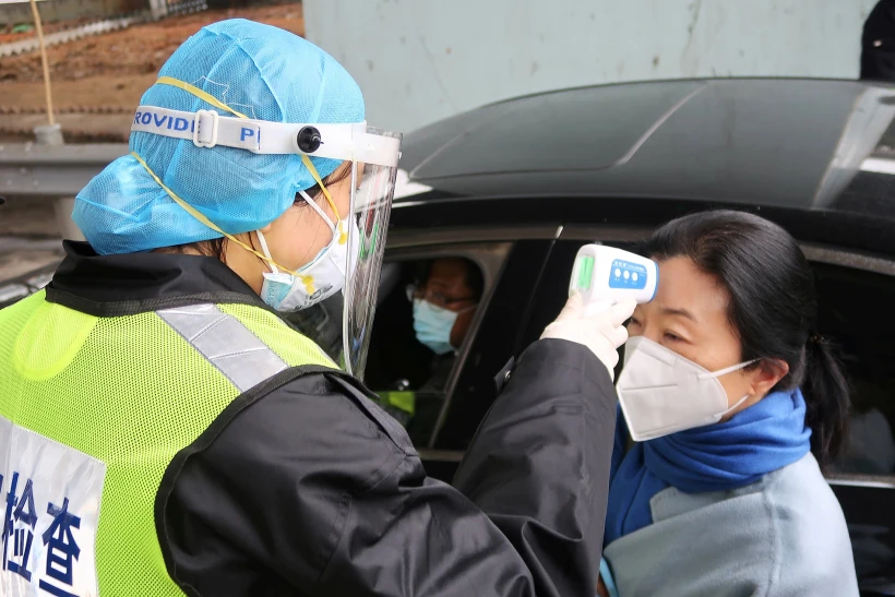 A Security Officer In A Protective Mask Checks The Temperature Of A Passenger Following The Outbreak Of A New Coronavirus, At An Expressway Toll Station On The Eve Of The Chinese Lunar New Year Celebrations, In Xianning