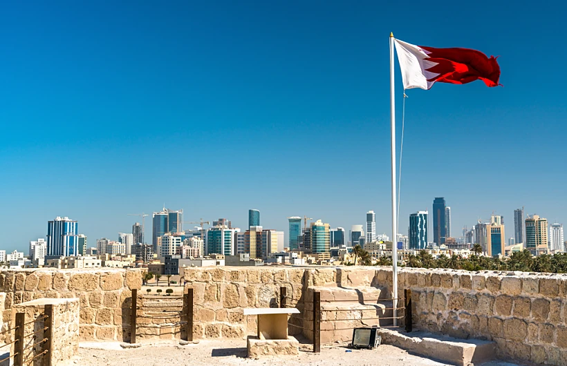 Bahrain,flag,with,skyline,of,manama,at,bahrain,fort.,a