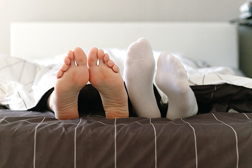 Barefoot,female,and,male,feet,in,socks,in,bed.,warm Blooded