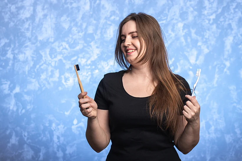 A,young,woman,with,a,smile,holds,two,toothbrushes,in