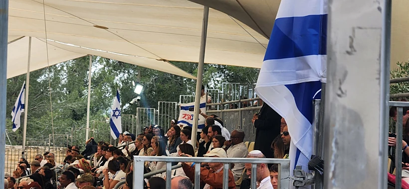אחד המשתתפים בטקס מניף דגל ישראל ועליו הכיתוב "7.10
