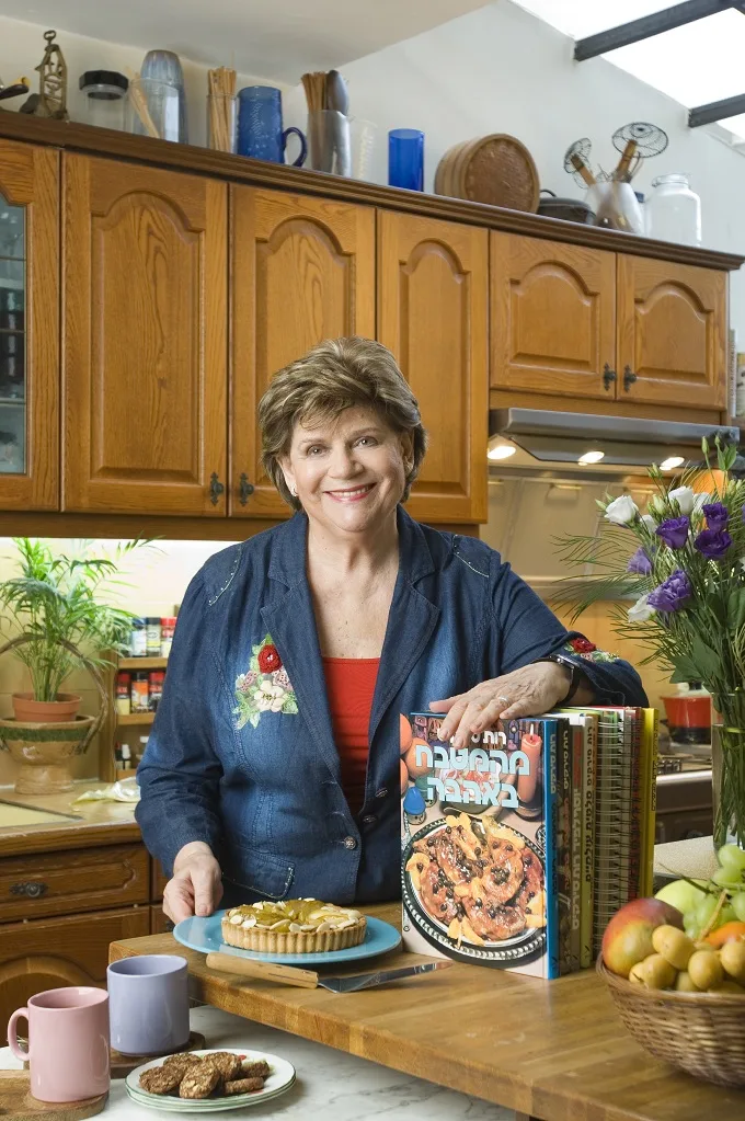 רות סירקיס במטבחה עם הספר "מהמטבח באהבה