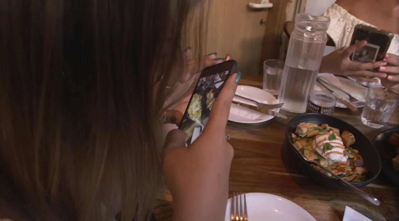 צעירה מצלמת את המנה שלה באמצעות הסמארטפון