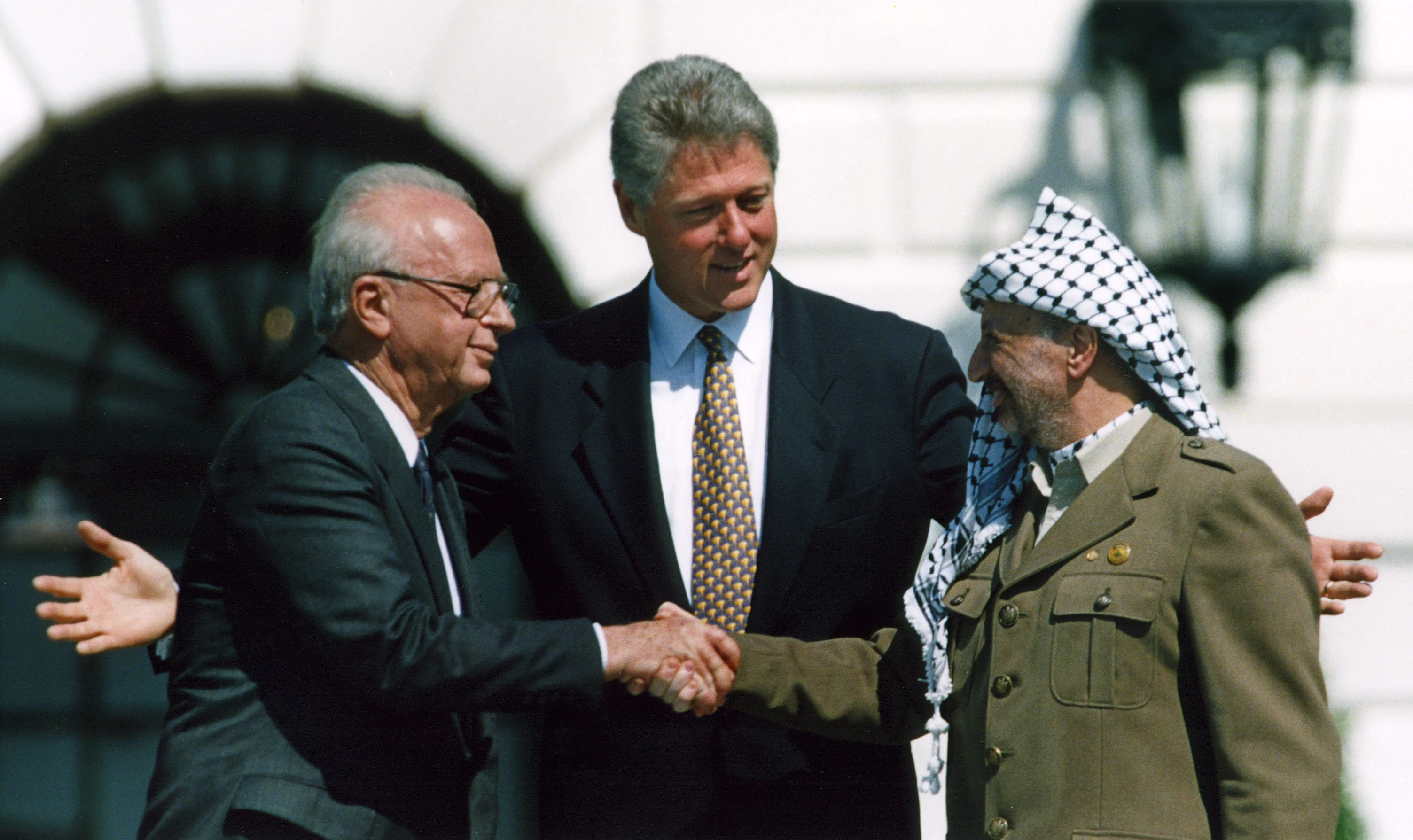 לחיצת היד המפורסמת בטקס חתימת הסכם אוסלו א' בין ישראל והפלסטינים ב-13 בספטמבר 1993 על מדשאת הבית הלבן בוושינגטון. יו''ר אש''ף יאסר ערפאת וראש הממשלה יצחק רבין לוחצים יד וביניהם הנשיא ביל קלינטון