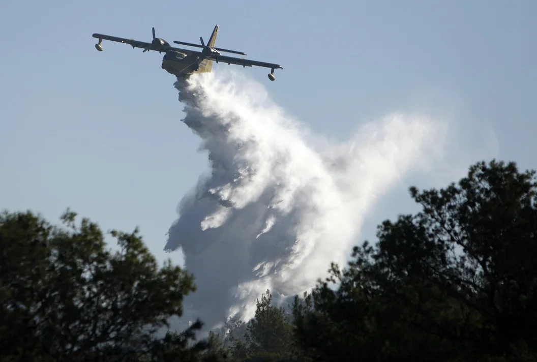מטוס שופך מיים לכיבוי להבות השריפה ביערות הכרמל