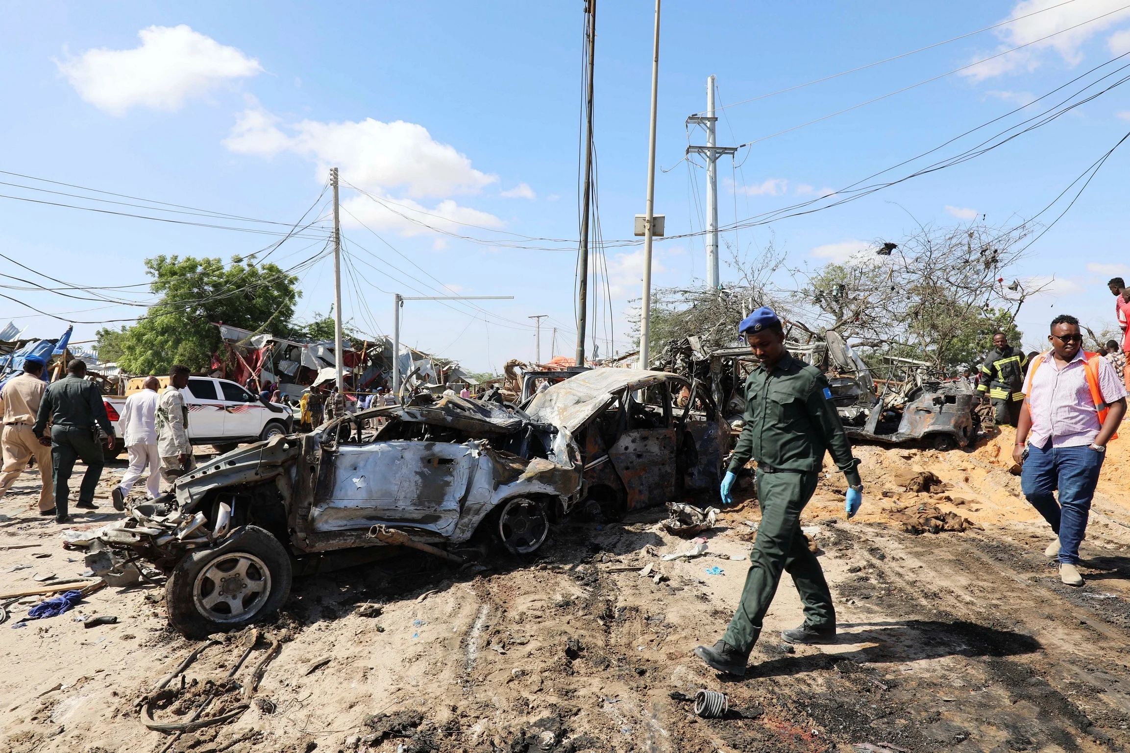 A Somali Police Officer Walks Past A Wreckage At The Scene Of A Car Bomb Explosion At A Checkpoint In Mogadishu