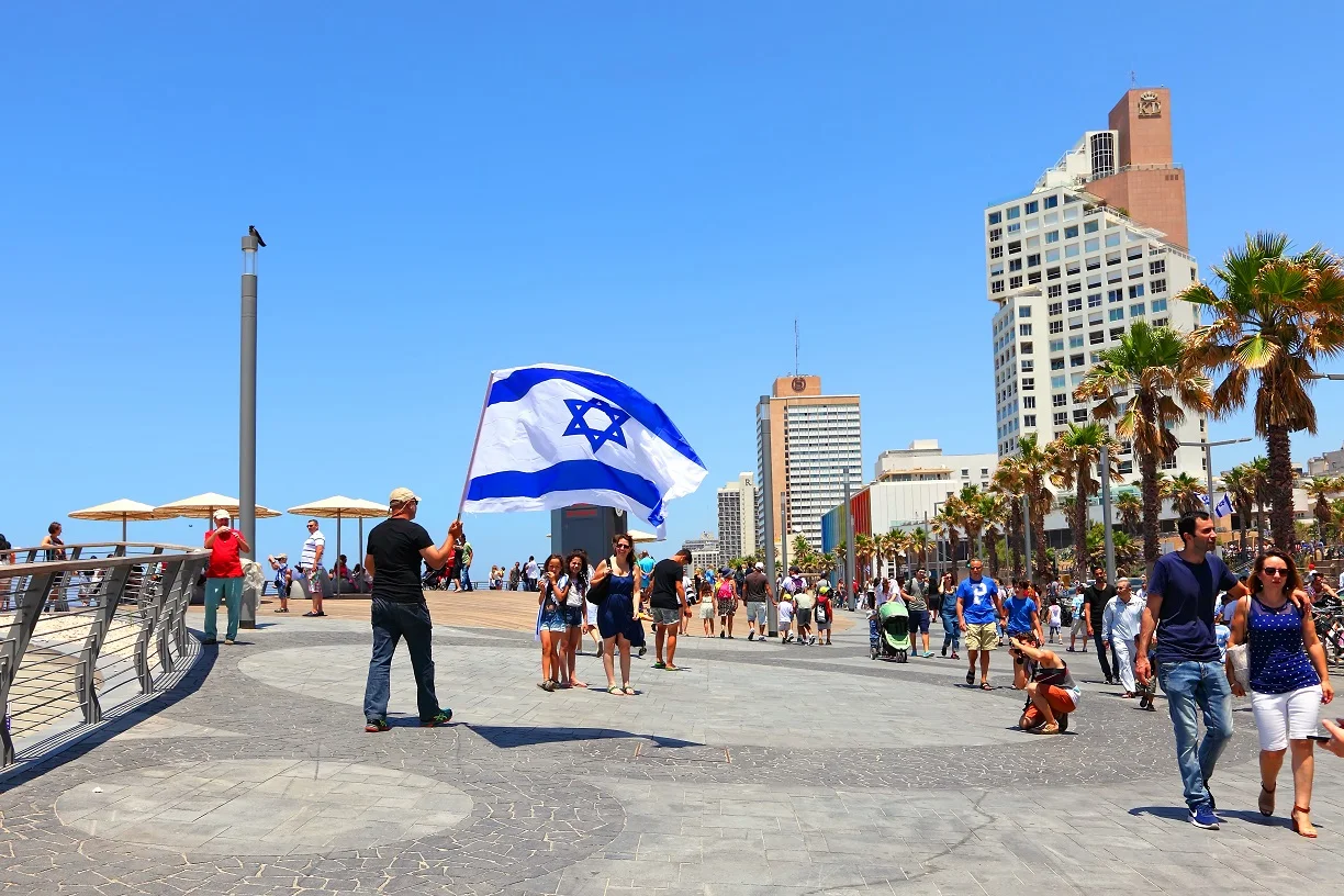 אזרח מניף דגל ישראל בטיילת תל אביב במהלך חגיגות יום העצמאות