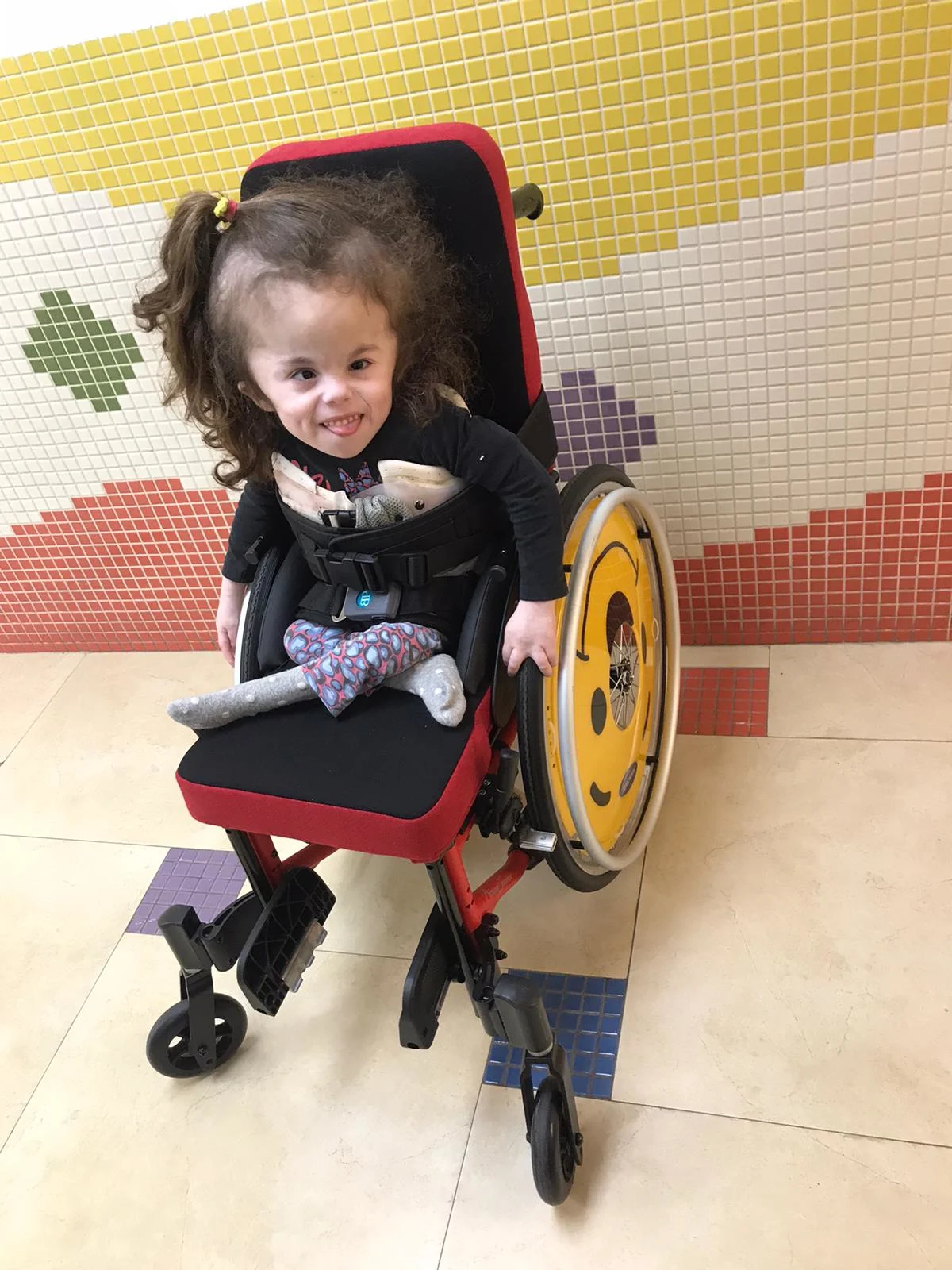 אביגיל חבושה בת החמש עם כיסא בגלגלים המיוחד שהותקן עבורה