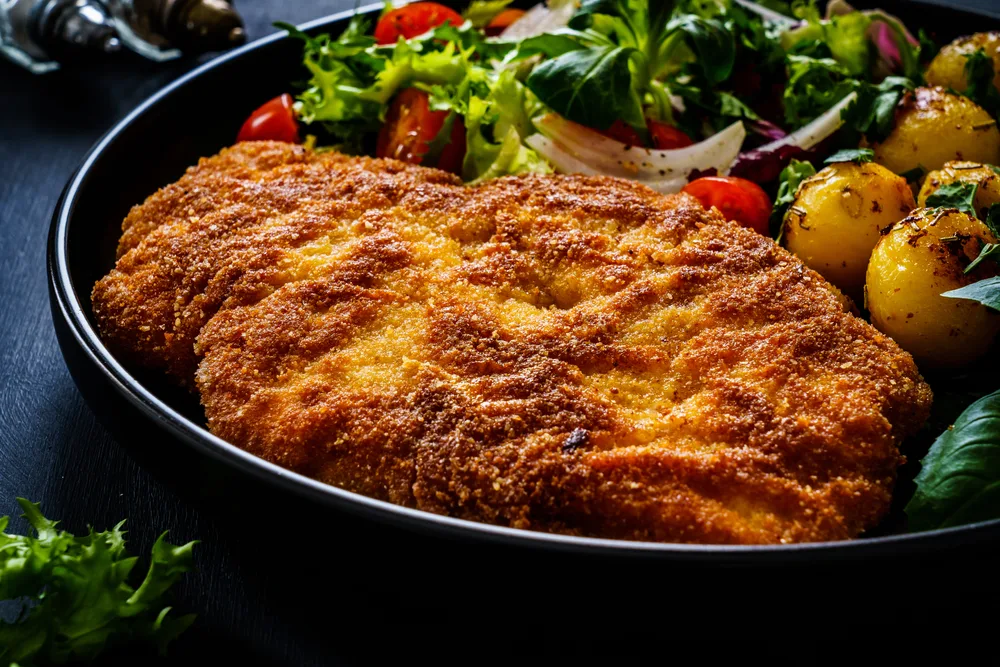 Breaded,fried,pork,chop,,fried,potatoes,and,vegetable,salad,on