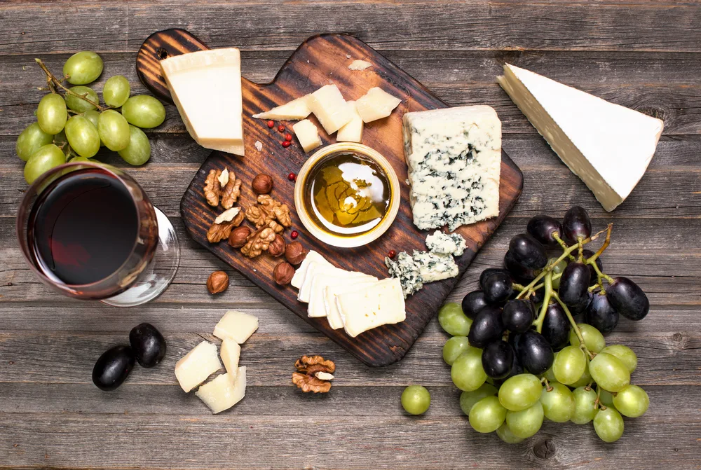 Grapes,,red,wine,,cheeses,,honey,and,nuts,over,rustic,weathered