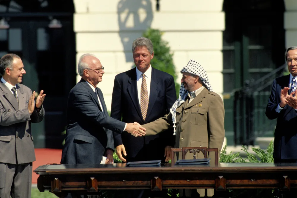 לחיצת היד המפורסמת בטקס חתימת הסכם אוסלו ב-13 בספטמבר 1993 על מדשאת הבית הלבן בוושינגטון. ערפאת, רה''מ יצחק רבין וביניהם הנשיא ביל קלינטון