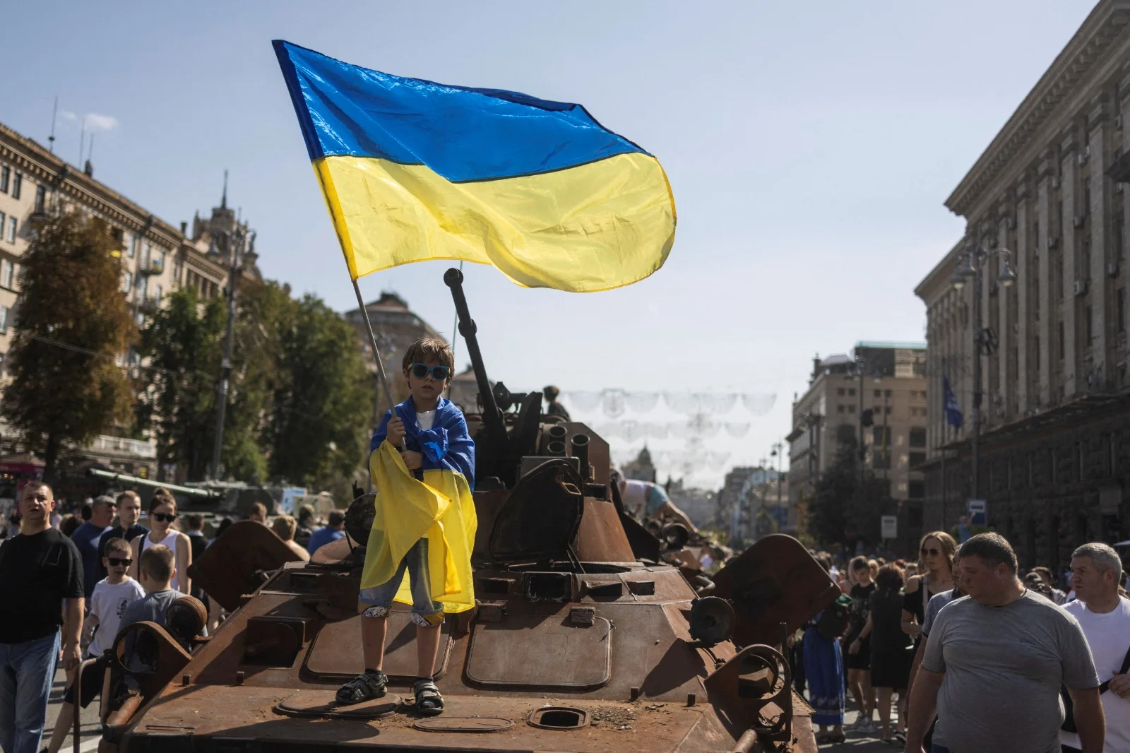 ילד מניף דגל אוקראינה על טנק רוסי הרוס בקייב