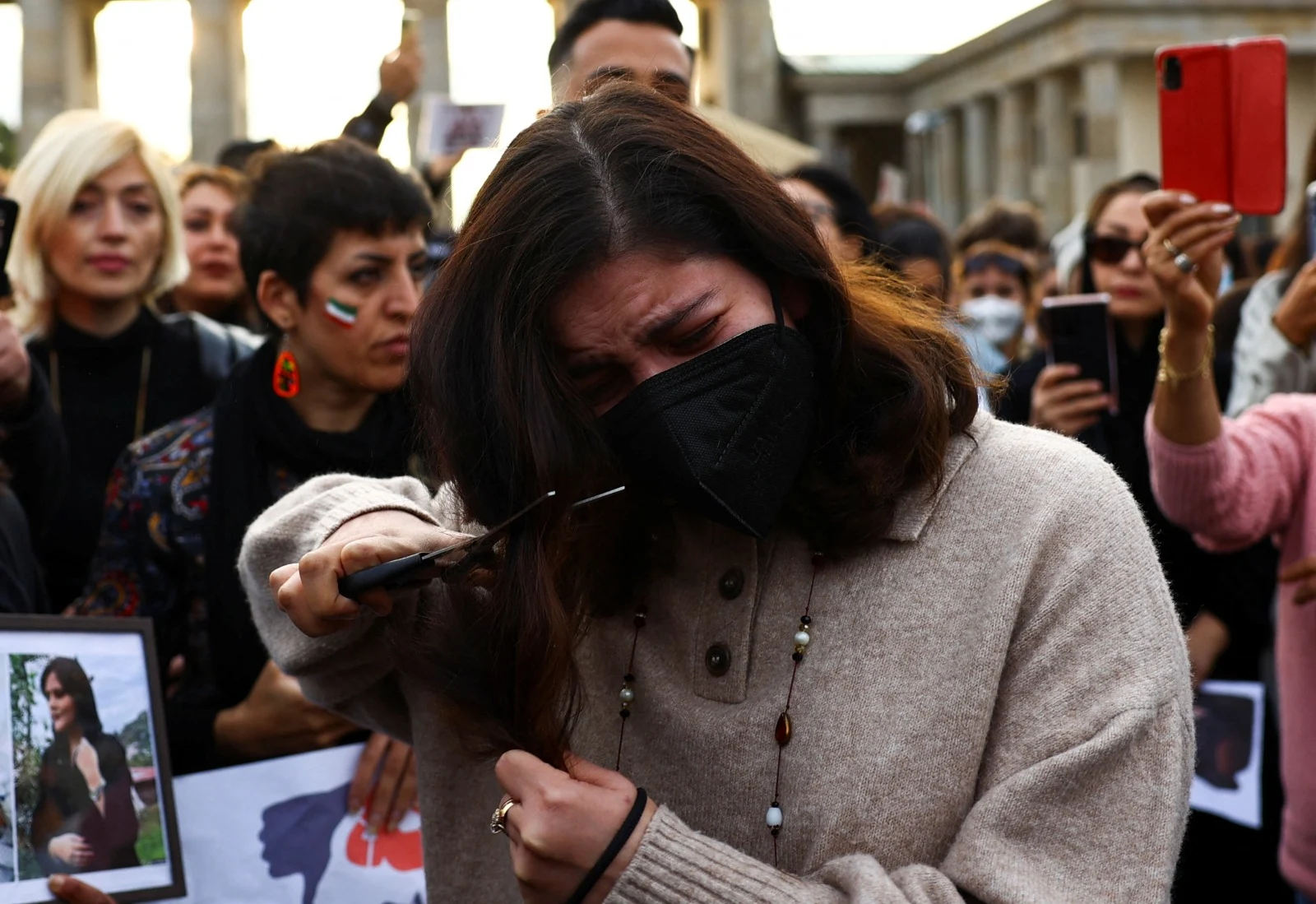 צעירה גוזרת את שיערה בהפגנה בעקבות מותה של מחסה אמיני בברלין השבוע