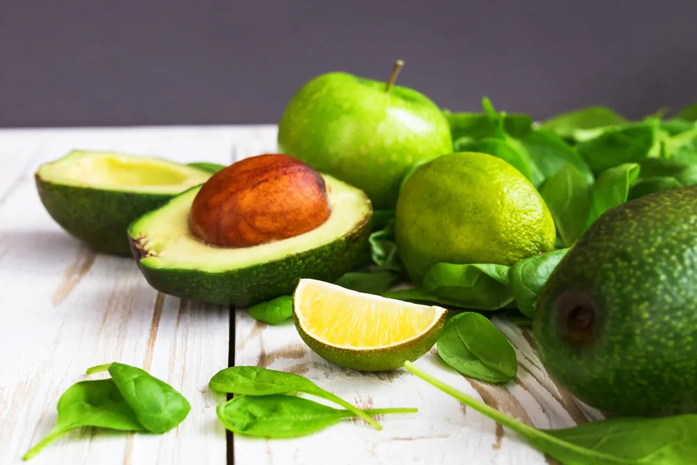 Wooden,background,with,healthy,green,spinach,,lime,,avocado,and,apple.