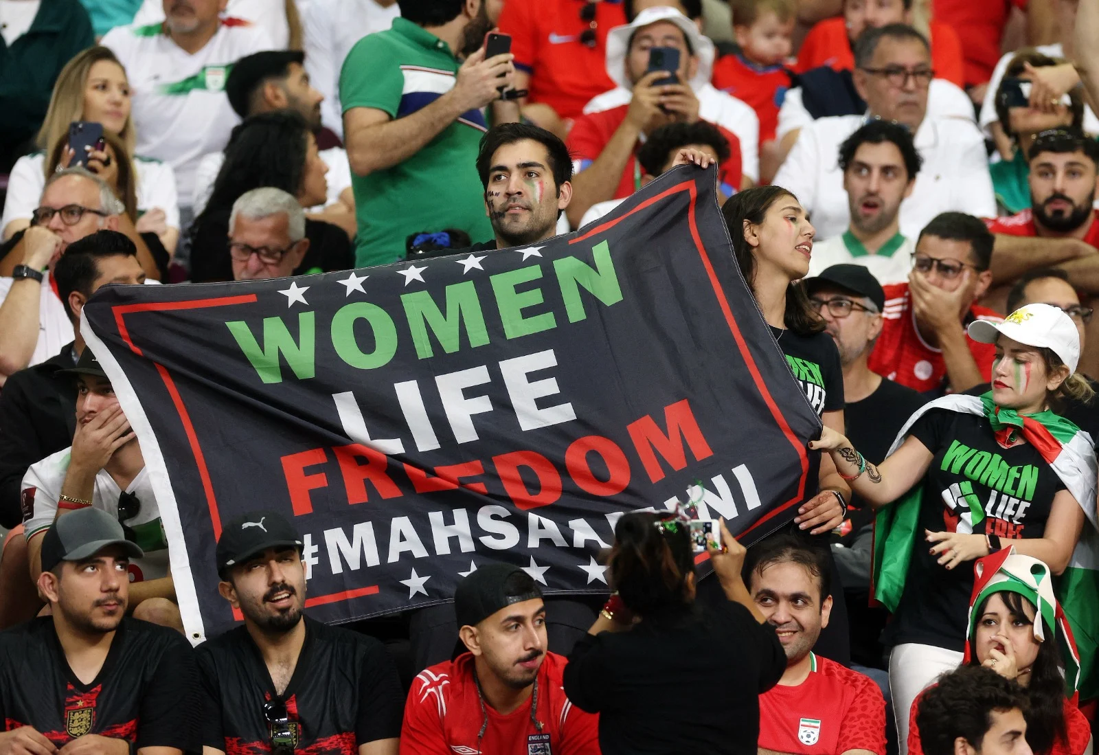 אוהד נבחרת איראן מניף שלט ''אישה, חיים, חופש''