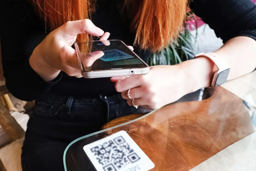 Woman,scanning,the,barcode,qr,code,in,restaurant,or,cafe