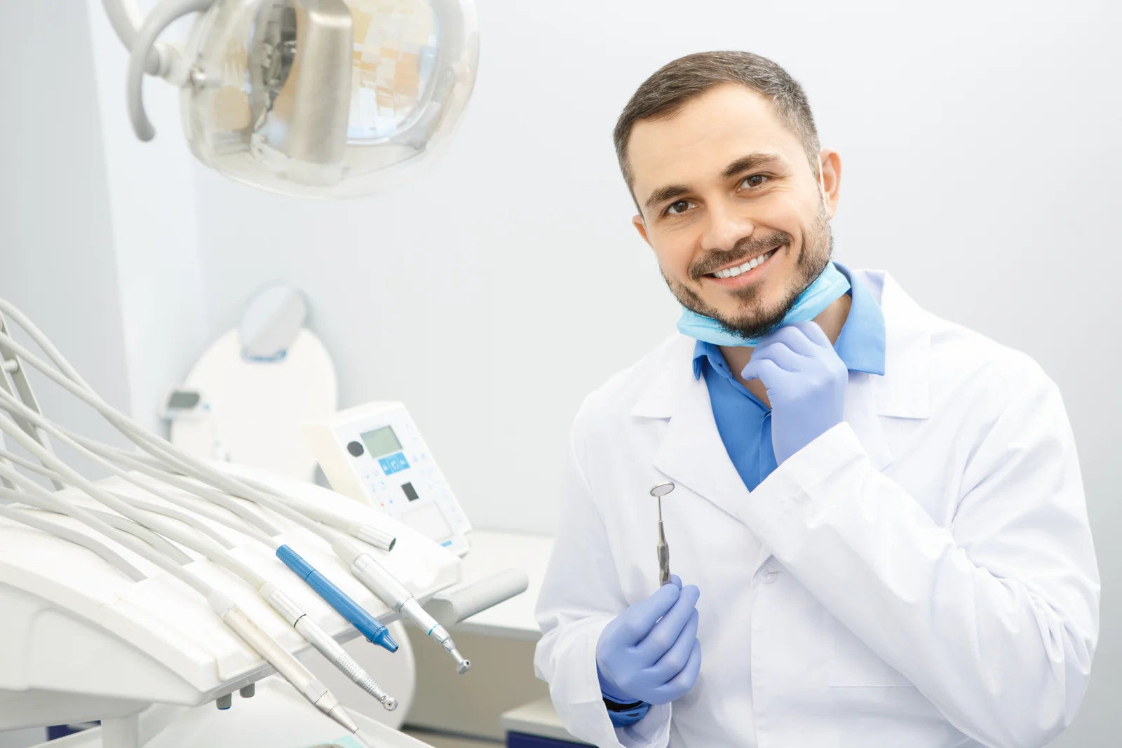 Professional,male,dentist,smiling,to,the,camera,holding,dental,instruments